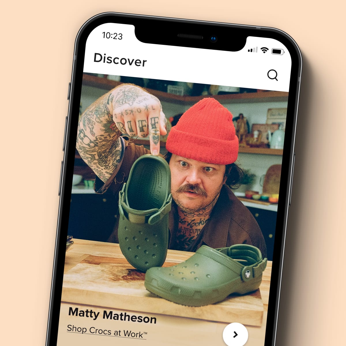 Matty Matheson gazing at some Crocs shown on a phone in the crocs app