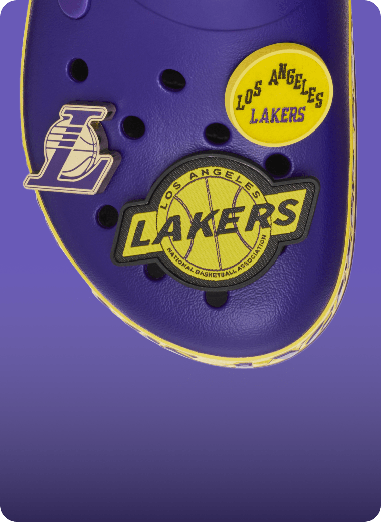 Close-up of a purple Crocs clog decorated with Lakers-themed charms and Lakers logo.