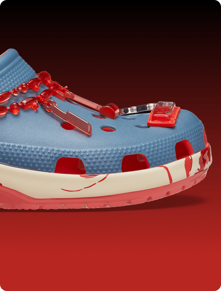 Blue clog with red chain details, dangling accessories, and red accents along the cream midsole.