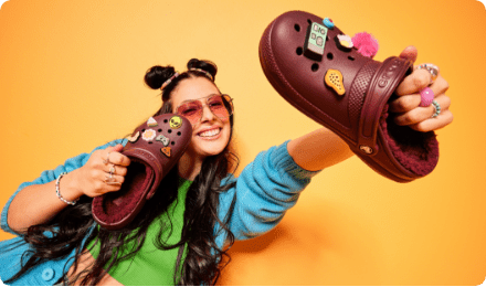 Model holding up fuzz-lined clogs filled with Jibbitz.