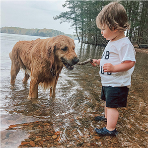 Kid in Crocs playing with dog.